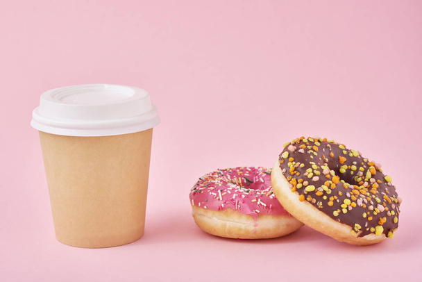 ピンクの背景にコーヒーとドーナツのカップ - 写真・画像