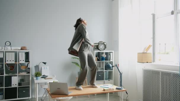 Slow motion of crazy girl dancing in office on desk taking off jacket throwing away - Materiał filmowy, wideo