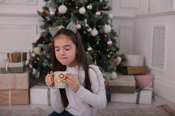 Різдвяний портрет красивої дівчини з довгим світлим волоссям в грайливому настрої зображує різні емоції
 - Фото, зображення