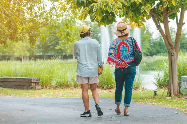 Επιστροφή άποψη της ευτυχίας των γυναικών φίλους περπάτημα μαζί δίπλα στο σιντριβάνι στο δημόσιο πάρκο. - Φωτογραφία, εικόνα