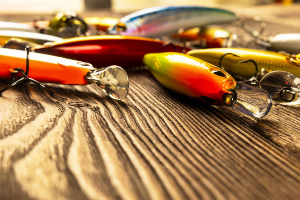 Fishing tackle background. Fishing tackles and wobbler on wooden board. Fishing hooks, lures and baits. Fishing gear on a dark table - Photo, Image