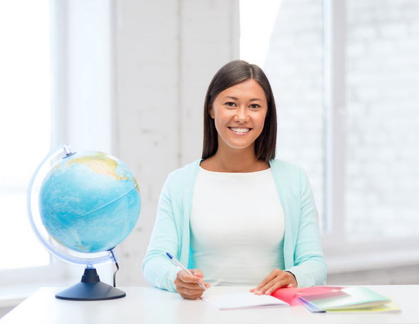 Teacher with globe and notepad at school - Foto, Imagen