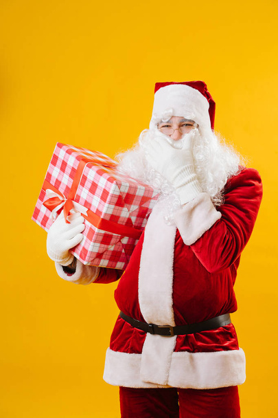 Happy Santa Claus with a present in hand stroking his beard. - Foto, Imagem
