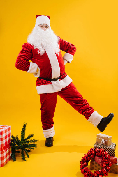 Happy dancing Santa Claus with hands on his waist extending leg - Photo, image