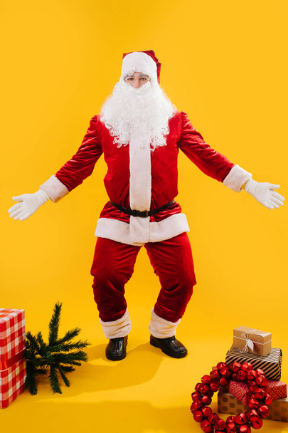 Feliz dança Papai Noel agachamento com as mãos e joelhos separados, como encolher os ombros
 - Foto, Imagem