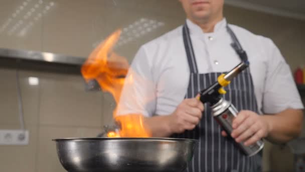 Koch kocht in Restaurantküche. Kochen mit Flamme, Zeitlupenaufnahmen von Flammen, die aus der Pfanne steigen. hd - Filmmaterial, Video