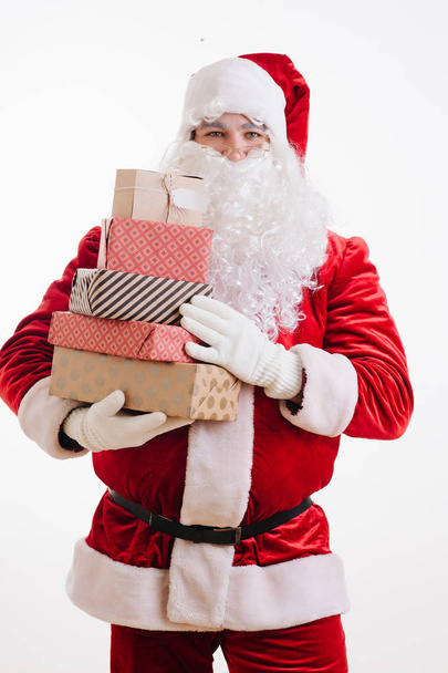 Happy satisfied Santa Claus holding stack of wrapped presents for christmas - Zdjęcie, obraz