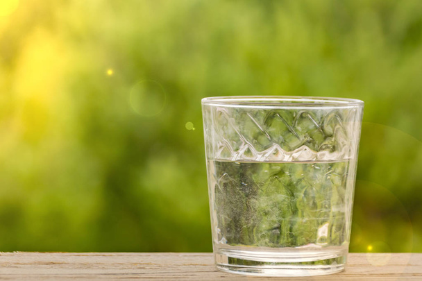 bicchiere d'acqua su un tavolo di legno sfondo di bokeh verde
 - Foto, immagini
