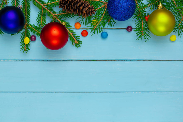 Boże Narodzenie z powrotem, ziemia, zielone gałązki jodły, czerwony i niebieski, żółty, piłka, cukierki, stożek, niebieskie deski - Zdjęcie, obraz