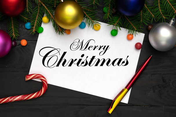 Joyeux Noël fond, branches de sapin vert, rouge et bleu, rose, boules jaunes, bonbons, drap blanc et un stylo
 - Photo, image