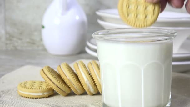 Dunking a vanilla cream sandwich cookie into a glass of milk, slow motion - Imágenes, Vídeo