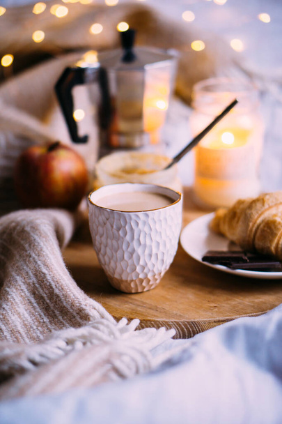 Cozy winter weekend breakfast, coffee and croissant on wooden tray - Photo, Image