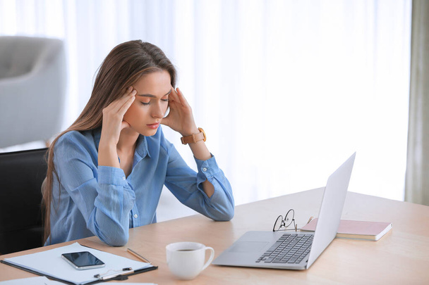 Stressed woman sitting at table in office - Foto, imagen