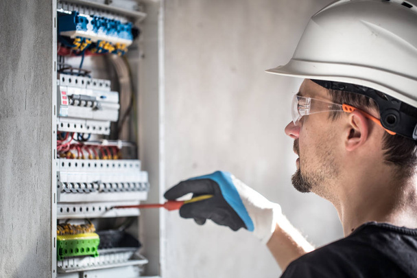 Hombre, un técnico eléctrico trabajando en una centralita con fusible
 - Foto, Imagen