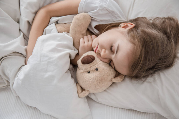 Милая маленькая девочка в постели с мягкой игрушкой
. - Фото, изображение