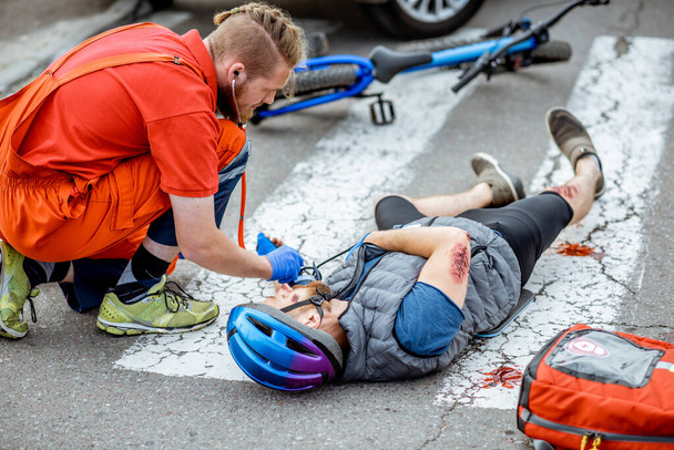 Médico aplicando primeros auxilios al herido en la carretera
 - Foto, imagen