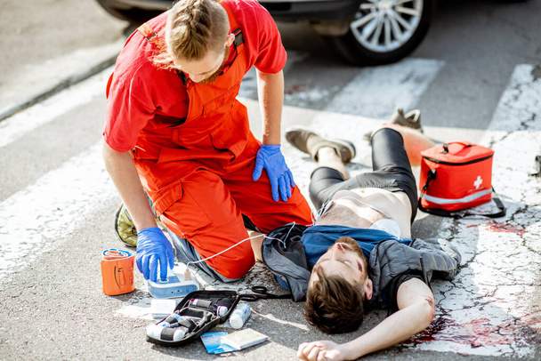 Médico aplicando atención de emergencia después del accidente de tráfico
 - Foto, Imagen
