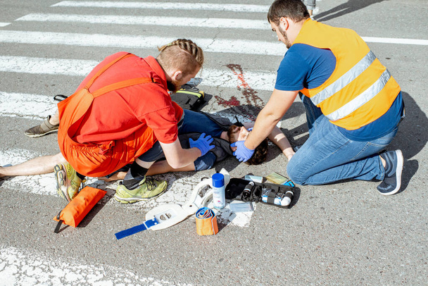 Медики застосовують екстрену допомогу постраждалому на дорозі
 - Фото, зображення