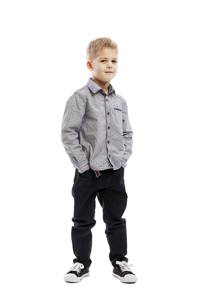 Standing serious preschool boy in a shirt and trousers. Isolated over white background.  - Photo, image