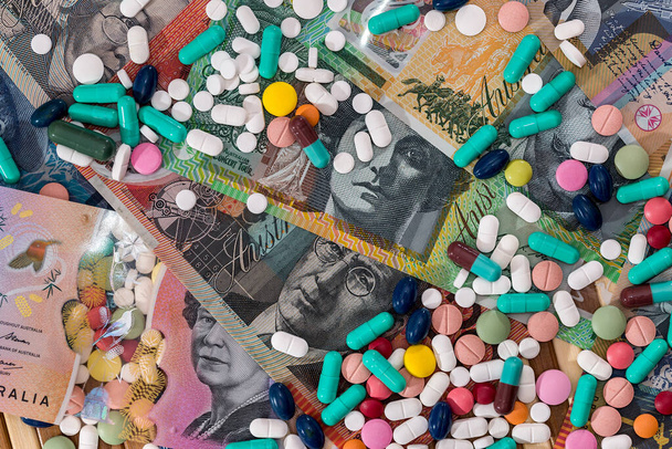 Pilules colorées dispersées sur les billets en dollars australiens
 - Photo, image