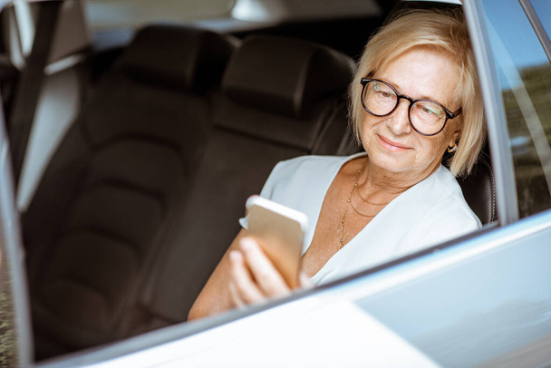 Starší žena s telefonem v autě - Fotografie, Obrázek