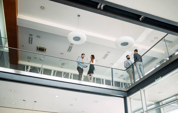 Modern business people walking on stairs in glass hall in office building - Foto, imagen