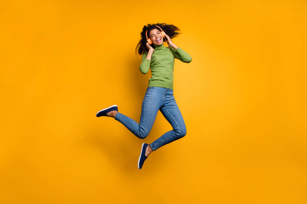 Full length body size photo of casual cheerful positive cute pretty girlfriend in jeans denim jumping listening to music isolated vivid color background - Foto, Imagen