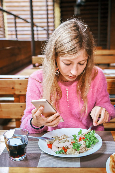 young girl in a cafe with a smartphone. woman having lunch - Photo, Image