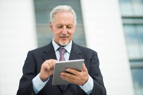 Businessman looking at his tablet outdoor in front of his office - Photo, Image
