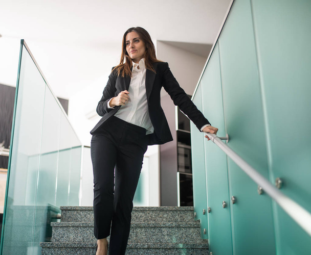 Young businesswoman walking down the stairs in her office - Фото, зображення