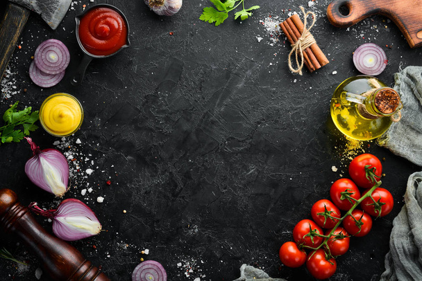 Black stone cooking background. Spices and vegetables. Top view. Free space for your text. - Фото, изображение