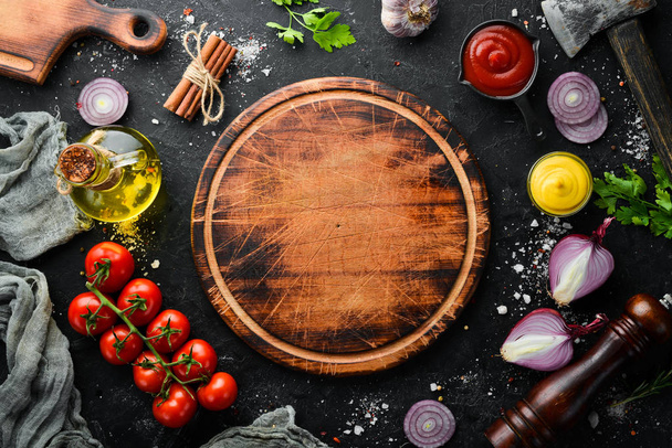 Black stone cooking background. Spices and vegetables. Top view. Free space for your text. - 写真・画像