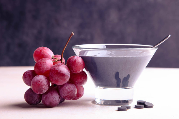 Black yogurt with activated carbon and red grapes - Photo, Image