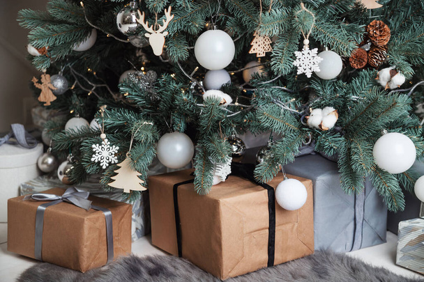 Gift boxes Packed in Kraft paper lie under the Christmas tree. - Foto, Imagem