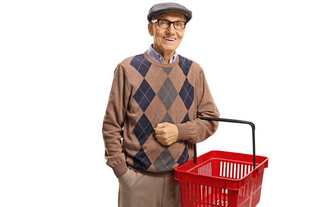 Elderly man smiling and holding a shopping basket  - Foto, afbeelding