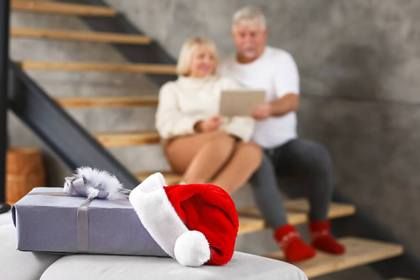 Christmas gift with Santa Claus hat at home of mature couple - Foto, Bild