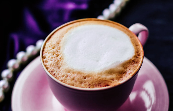 Kopje cappuccino voor ontbijt met satijnen en parels sieraden  - Foto, afbeelding