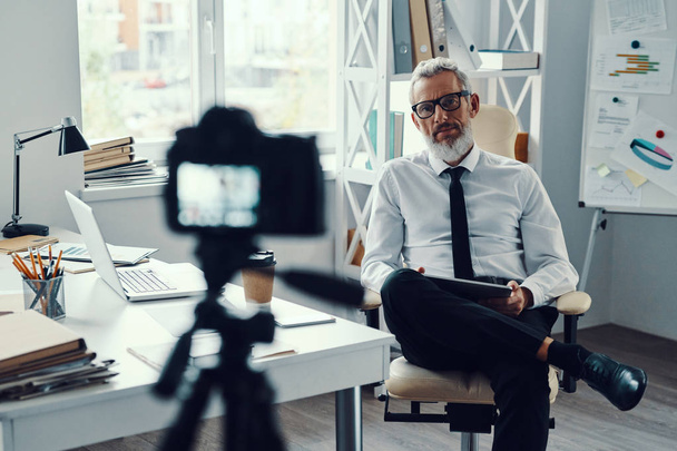 Confident mature man in elegant shirt and tie telling something while making social media video - Valokuva, kuva