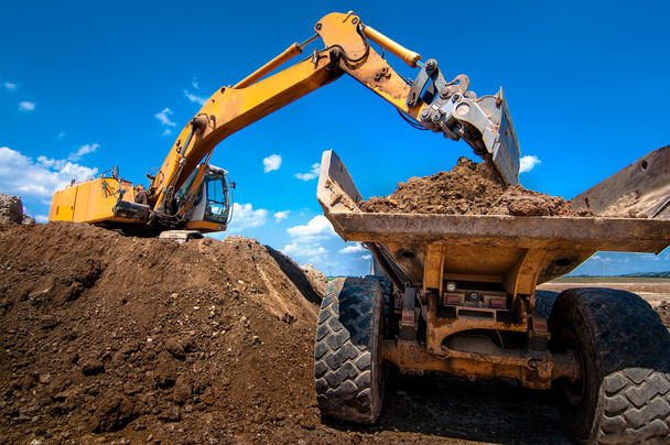 Yellow excavator loading soil into a dumper truck - Photo, Image