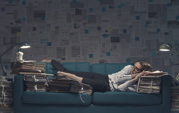 Stressed businesswoman sleeping on a couch with lots of paperwor - Foto, Imagen