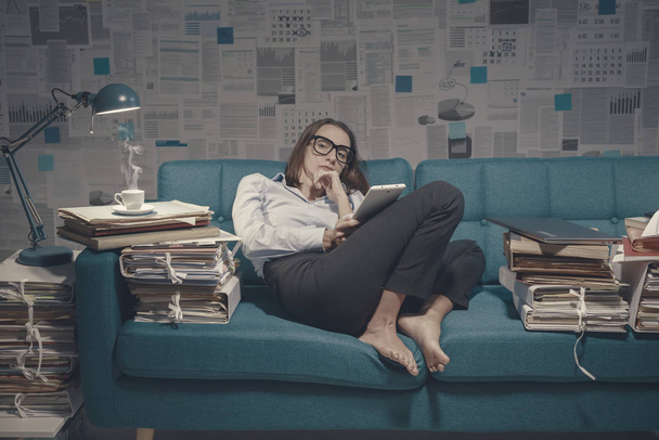 Tired businesswoman sitting on the sofa and connecting - Fotografie, Obrázek