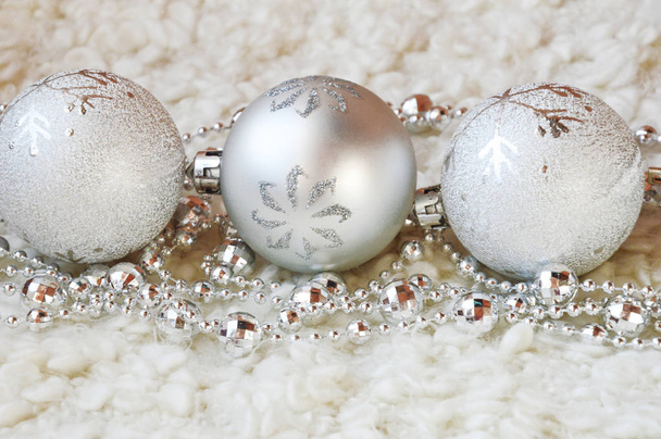 Decor for a happy Christmas and New year. Silver color. Christmas balls and beads on a white cozy blanket. happy winter holidays. Background for congratulations. Grey balls for Christmas tree decoration. - Photo, image