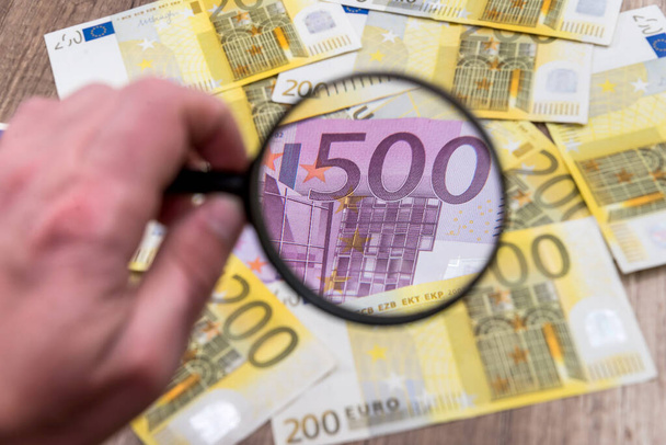 虫眼鏡を持つ男を見つけるユーロ紙幣 - 写真・画像
