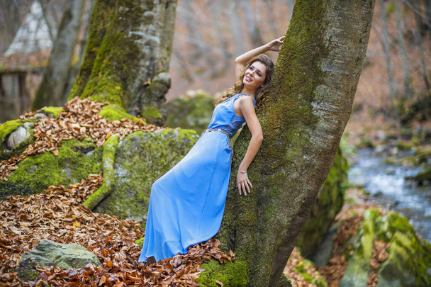 vrouw in blauwe jurk in de buurt van een rivier in de herfst dag - Foto, afbeelding