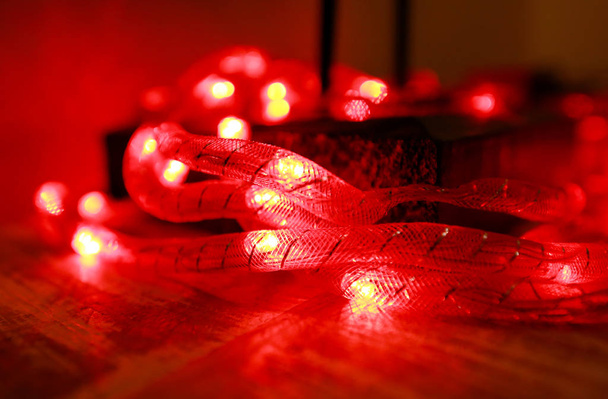 Helder rood Nieuwjaar en kerst rijstverlichting, ondiepe scherptediepte. Abstracte rode licht achtergrond. Decoratieve knipperende lichten, ornamenten om kerst te vieren, vakantie scene. Kerstconcept. - Foto, afbeelding