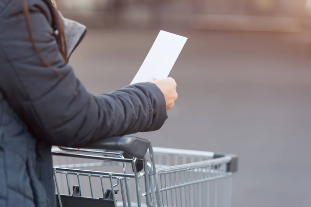 Woman pushing shopping cartand reading a list  - Fotoğraf, Görsel