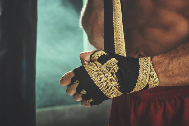 Close-up de um boxeador amarrando bandagem protetora em torno de seus pulsos
 - Foto, Imagem