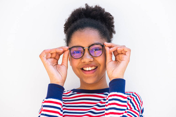 Close up portrait of young african american girl holding eyeglasses and smiling by white background - Photo, Image