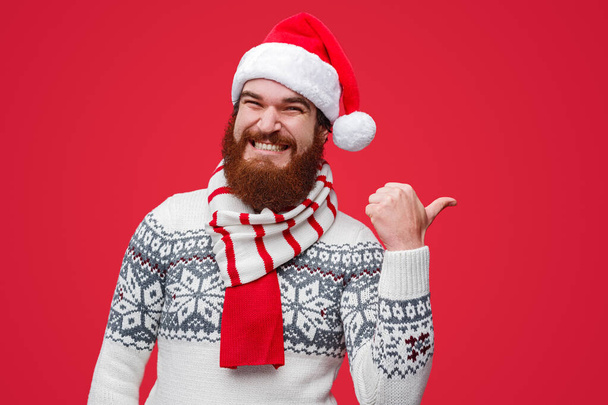 Happy male in Santa hat pointing away - Photo, Image