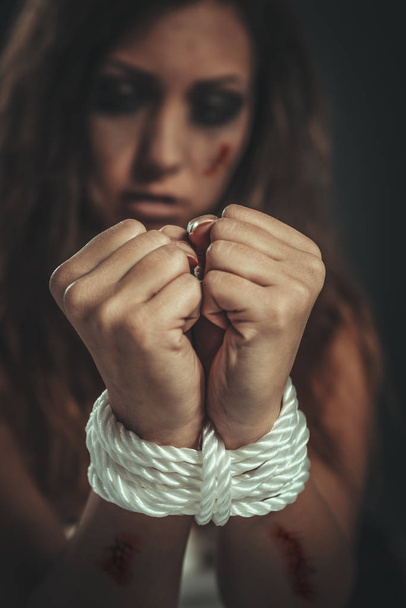 Zoufalá unesená žena uvázaná provazem ve tmě, čekající na pomoc. Selektivní zaměření, zaměření na lano. - Fotografie, Obrázek